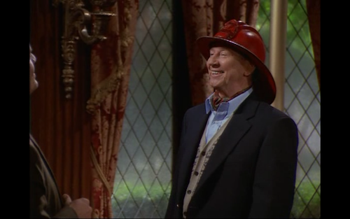 Donald O'Connor wearing a red fireperson's hat.