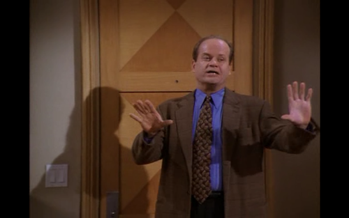 Frasier holds up two hands to convince people to do something. 